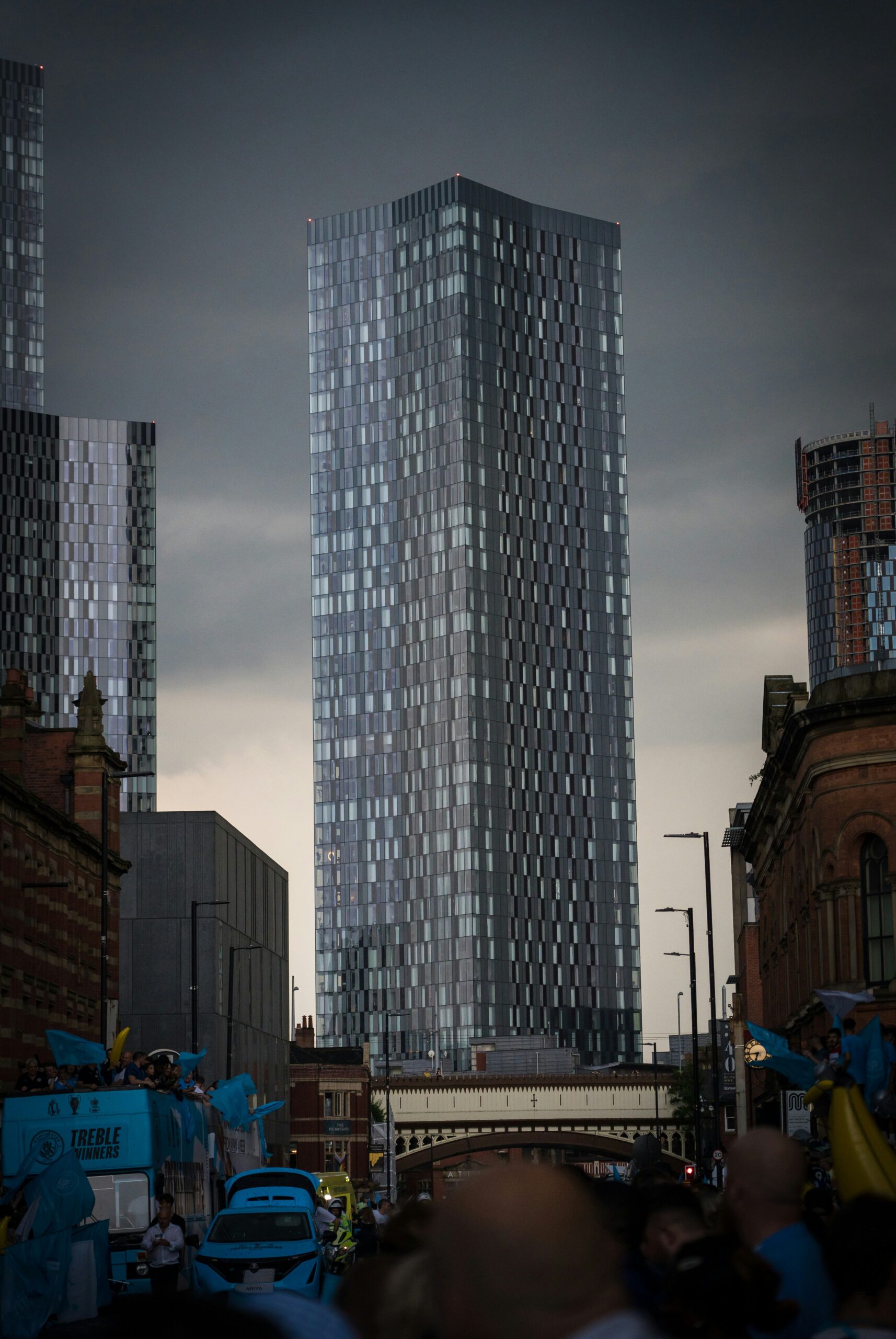 a group of people walking down a street next to tall buildings